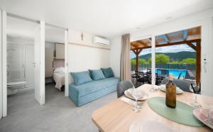 a living room with a blue couch and a bedroom at Mobile Home Kapo I Exclusive Mobile Home with Private Pool in Sitno Donje