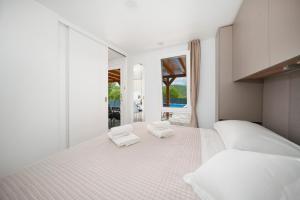 a white bedroom with two white towels on a bed at Mobile Home Kapo I Exclusive Mobile Home with Private Pool in Sitno Donje +57 photos