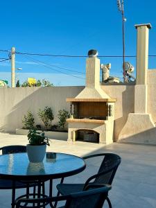 a patio with a table and chairs and a fireplace at Athens Layover Home in Koropíon