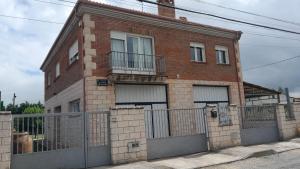 a brick house with a gate and a fence at El refugio de Sam in Burgos