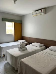 a room with three beds with a stuffed animal sitting on top at Pousada Lagoa Seca in Juazeiro do Norte