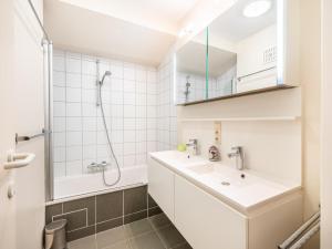 a white bathroom with a sink and a shower at Anais derde in Sint-Idesbald +9 photos