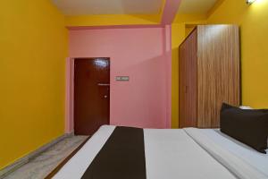a bedroom with yellow and pink walls and a bed at Hotel O by OYO Red Rose Near Noapara Metro Station in Kolkata