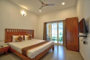 ein Schlafzimmer mit einem Bett mit Fernseher und einem Balkon in der Unterkunft Goa Radha Krishna holiday in Calangute