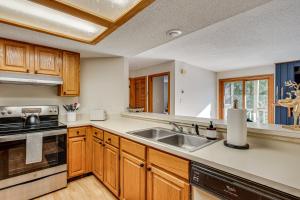 a kitchen with wooden cabinets and a sink at Riverfront Lincoln Condo w/ Patio + Pool Access! in Lincoln