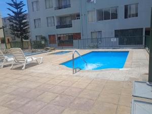 a swimming pool with two chairs and a building at Moderno Depto 1D con Estacionamiento Gratis Ideal Trabajo in Antofagasta