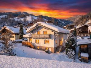 ein schneebedecktes Haus mit Sonnenuntergang im Hintergrund in der Unterkunft Alpen Haus Maria Top 2 in Viehhofen + 6 Fotos