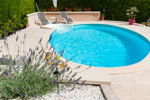 a swimming pool in a yard with chairs and flowers at Gîte au Ventoux in Villes-sur-Auzon +3 photos