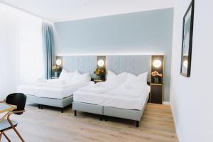three beds in a room with white sheets at Florum Hotel in Vienna