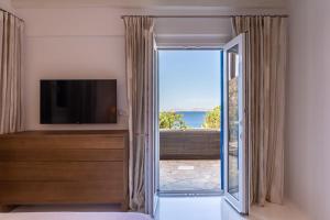 a living room with a tv and a sliding glass door at Villa Macaro with Direct Beach Access in Mikonos