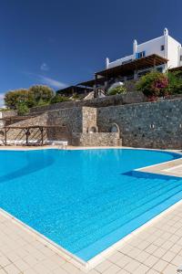a large blue swimming pool next to a building at Villa Macaro with Direct Beach Access in Mikonos
