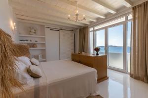 a bedroom with a bed and a large window at Villa Macaro with Direct Beach Access in Mikonos +52 photos