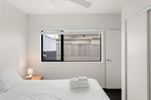 een slaapkamer met een wit bed en een raam bij NEW - 2BR Beachfront unit at Okitu Beach! in Gisborne