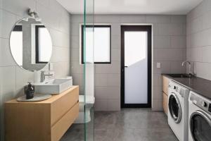 een badkamer met wastafel en wasmachine bij NEW - 2BR Beachfront unit at Okitu Beach! in Gisborne