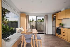 een keuken en woonkamer met een tafel en stoelen bij NEW - 2BR Beachfront unit at Okitu Beach! in Gisborne
