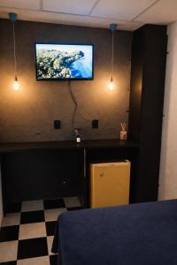 a room with a television on a wall with a checkered floor at Peró Beach Hospedaria in Cabo Frio +9 photos