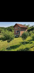 een groot bakstenen huis in een veld met twee bomen bij Katun in Kosovska Mitrovica