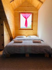 una camera da letto con un letto con una finestra con una tenda rosa di Brvnara Duga njiva a Čelinac