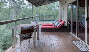 een veranda met een bank en een tafel op een terras bij Wild Edge Retreat in Wollombi