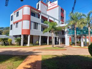 a building with palm trees in front of it at Hotel San Andres in Coronel Oviedo