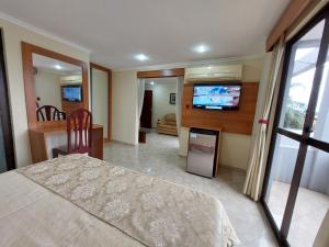 a bedroom with a bed and a flat screen tv at Hotel San Andres in Coronel Oviedo