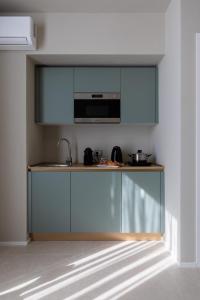 een keuken met blauwe kasten en een magnetron bij Cozy Rooms in Senorbì +10 foto's