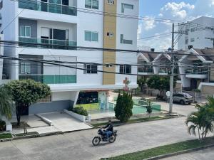 a man riding a motorcycle in front of a building at Apartaestudio La Castellana in Montería +4 photos