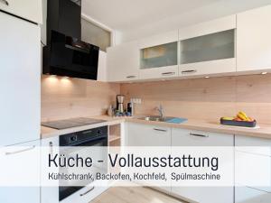 eine Küche mit weißen Schränken und der Aufschrift „Kirklie Vollstablerei“ in der Unterkunft Stadtdomizil Ziegelfeld - Ruhig & Zentral, 65" TV, Südbalkon, vollausgestattete Küche, Altstadt fußläufig, Bahnhof 5-10 Min, Tiefgarage im Haus, in Waldshut-Tiengen