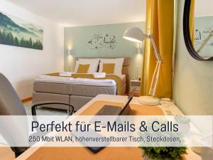 ein Schlafzimmer mit einem Bett und einem Schreibtisch mit einem Computer in der Unterkunft Stadtdomizil Ziegelfeld - Ruhig & Zentral, 65" TV, Südbalkon, vollausgestattete Küche, Altstadt fußläufig, Bahnhof 5-10 Min, Tiefgarage im Haus, in Waldshut-Tiengen