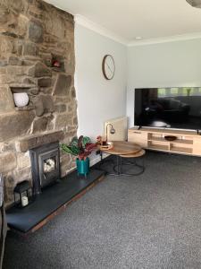 a living room with a stone fireplace and a table at Ty Newydd in Llangyniew