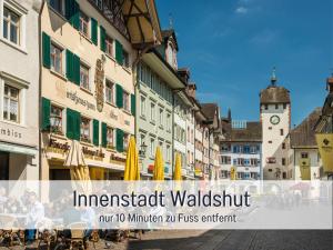 eine Straße mit Tischen und Sonnenschirmen und einem Uhrturm in der Unterkunft Stadtdomizil Ziegelfeld - Ruhig & Zentral, 65" TV, Südbalkon, vollausgestattete Küche, Altstadt fußläufig, Bahnhof 5-10 Min, Tiefgarage im Haus, in Waldshut-Tiengen + 47 Fotos