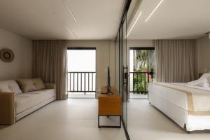 una camera da letto con un letto e un divano di Jubarte Flats a Itacaré Altre 30 foto