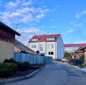 een wit huis met een rood dak op een straat bij Jan Gustav Apartments in Liptovský Mikuláš