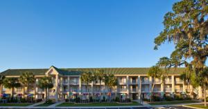 an exterior view of a hotel with palm trees at Days Inn by Wyndham Port Charlotte Town Center in Port Charlotte