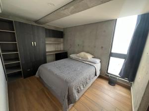 a small bedroom with a bed and a window at Penthouse en Centro de Monterrey in Monterrey