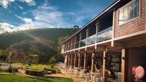 a building with a hill in the background at Pousada Finca dos Anjos in Passa Quatro