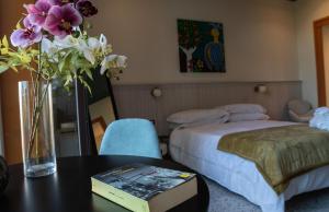 een slaapkamer met een bed en een vaas met bloemen op een tafel bij Des Bains Acireale in Acireale