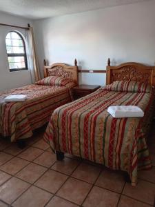 twee bedden in een kamer met een tegelvloer bij Villas Tonantzintla in Cholula