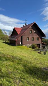 a large brown barn with a red roof in a field at Penzion Soukupovi in Strážné