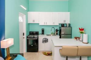 a kitchen with white cabinets and a blue wall at J & B Studio Apartment in Saint Johnʼs