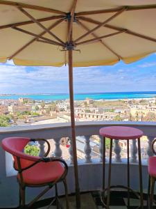 uma varanda com 2 cadeiras e um guarda-sol em أراكِ قريبا صينين فقط em Marsa Matruh