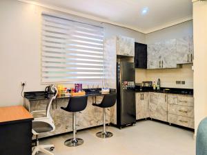 La cuisine est équipée d'un réfrigérateur et de deux tabourets de bar. dans l'établissement Hakuna Matata Apartment in Munyonyo, à Kampala
