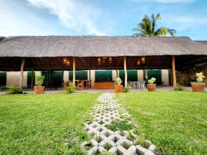 een gebouw met een rieten dak en een grasveld bij Hotel Otoch Apartments in Telchac