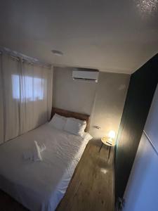 a small bedroom with a white bed and a table at בית אירוח מרום במדבר in Dimona