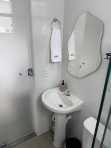 ein weißes Badezimmer mit Waschbecken und Spiegel in der Unterkunft Studio 218, Lavras, Minas Gerais in Lavras