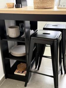 Ein schwarzer Hocker steht unter einem Tisch mit Tellern. in der Unterkunft Studio 218, Lavras, Minas Gerais in Lavras + 5 Fotos