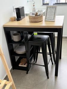 ein Tisch mit einem schwarzen Hocker und ein Tisch mit Tellern in der Unterkunft Studio 218, Lavras, Minas Gerais in Lavras