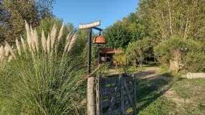 een tuin met een bord aan een hek en bomen bij La Paz suites de campo in Capilla del Señor
