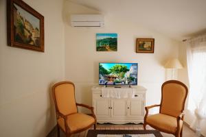 ein Wohnzimmer mit zwei Stühlen und einem Fernseher in der Unterkunft LaPetite Maison Abigail, Peaceful home in Avignon in Avignon