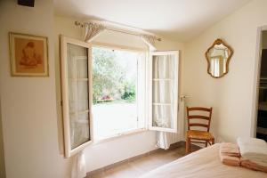 ein Schlafzimmer mit einem Fenster und einem Bett und einem Stuhl in der Unterkunft LaPetite Maison Abigail, Peaceful home in Avignon in Avignon